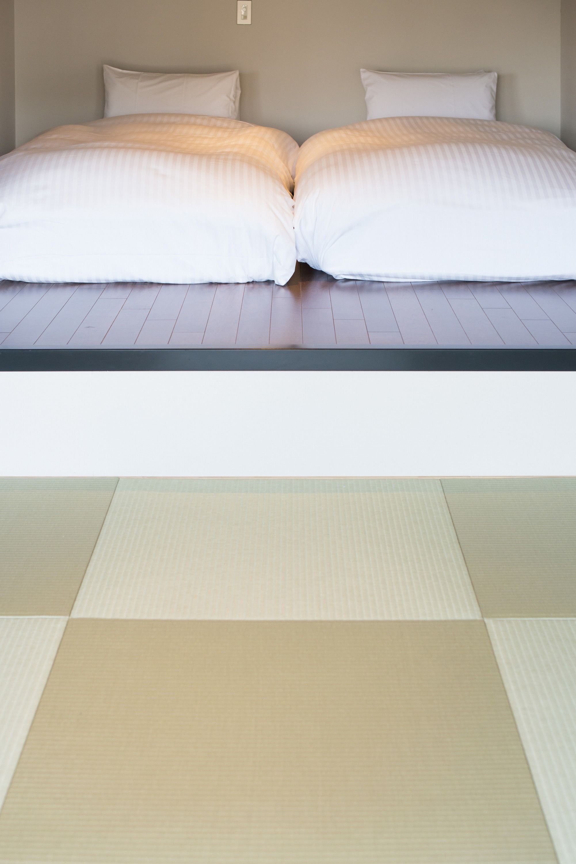 Una cama con dos almohadas y un colchón sobre un suelo de madera.