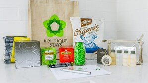 Variedad de artículos de viaje, incluyendo una bolsa con la etiqueta 'Boutique Stays', chips orgánicas, té Twinings y artículos de aseo.