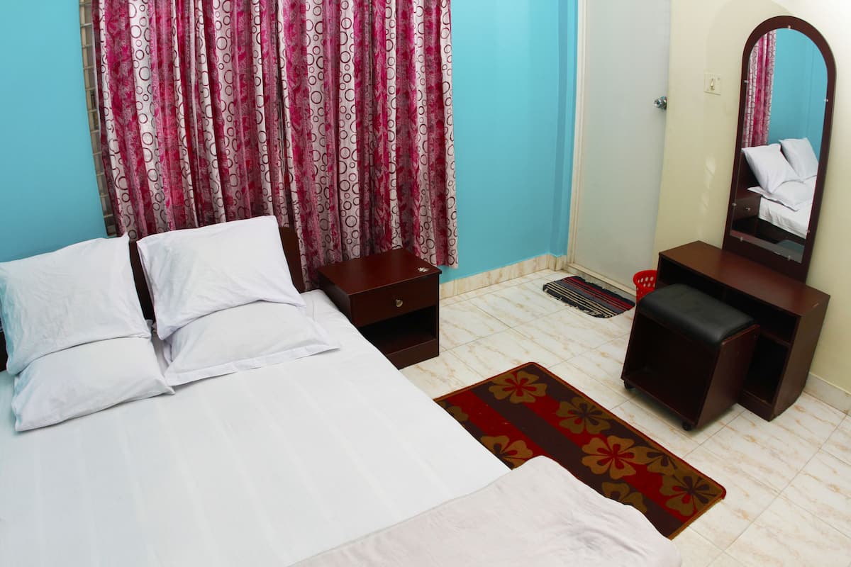 A bedroom with a bed, a dresser, a mirror, and a patterned rug.
