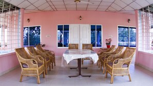 Une pièce avec une table et des chaises, de grandes fenêtres et un ventilateur de plafond.