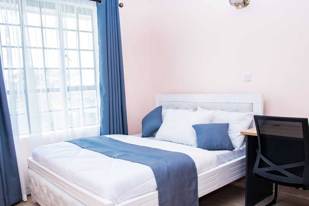 A bedroom with a bed, a chair, and a window with curtains.