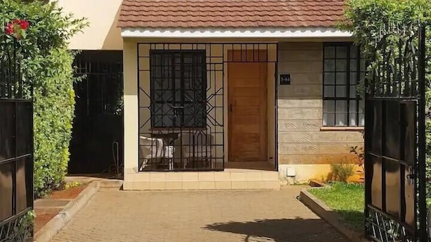 A two-story house with a tiled roof, a front door, and a small porch area.