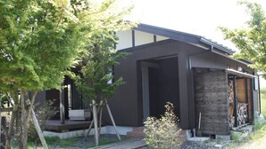 A modern house with a covered porch, a stone wall, and a wooden deck.