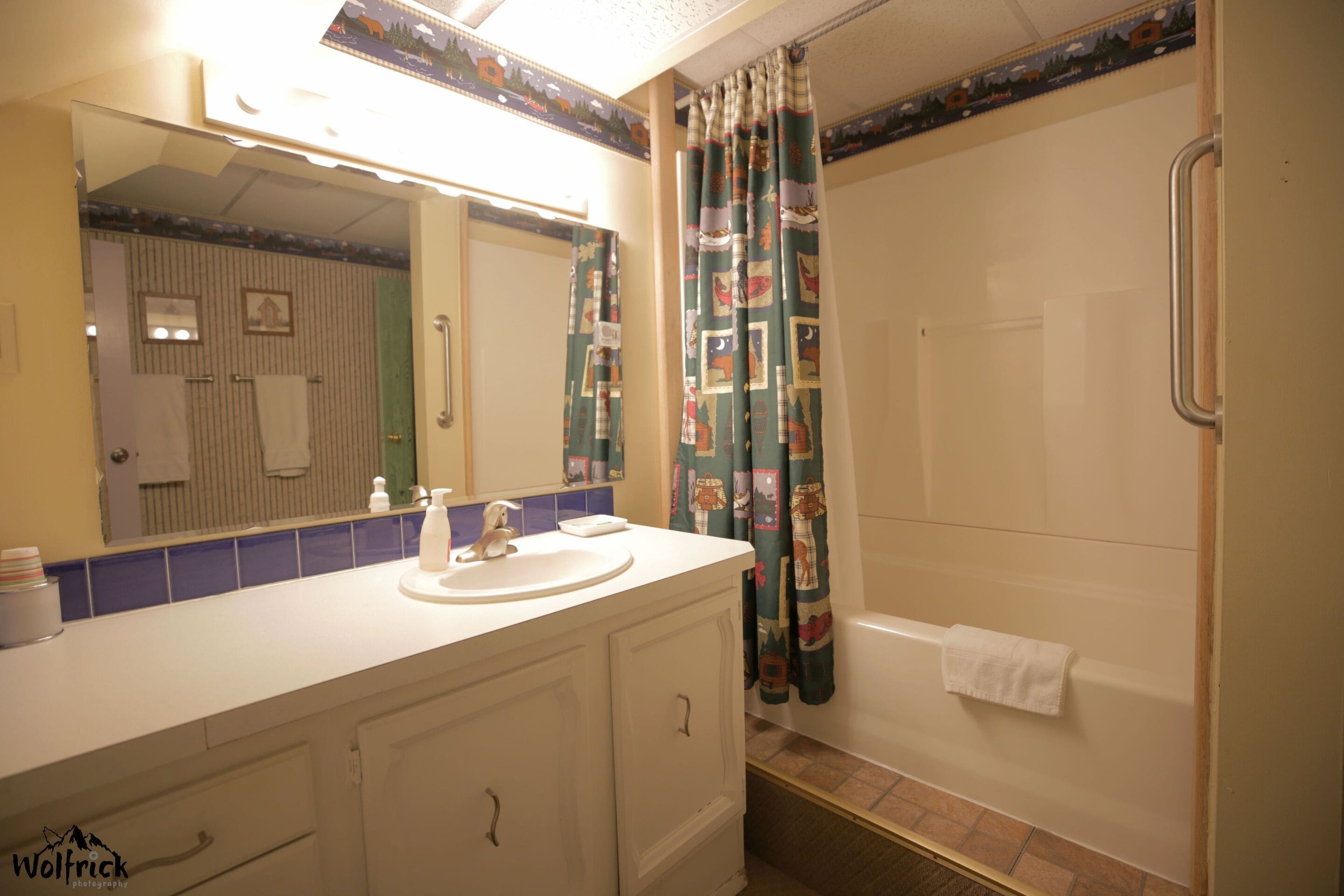 Un baño con lavamanos blanco, espejo y cortina de ducha.