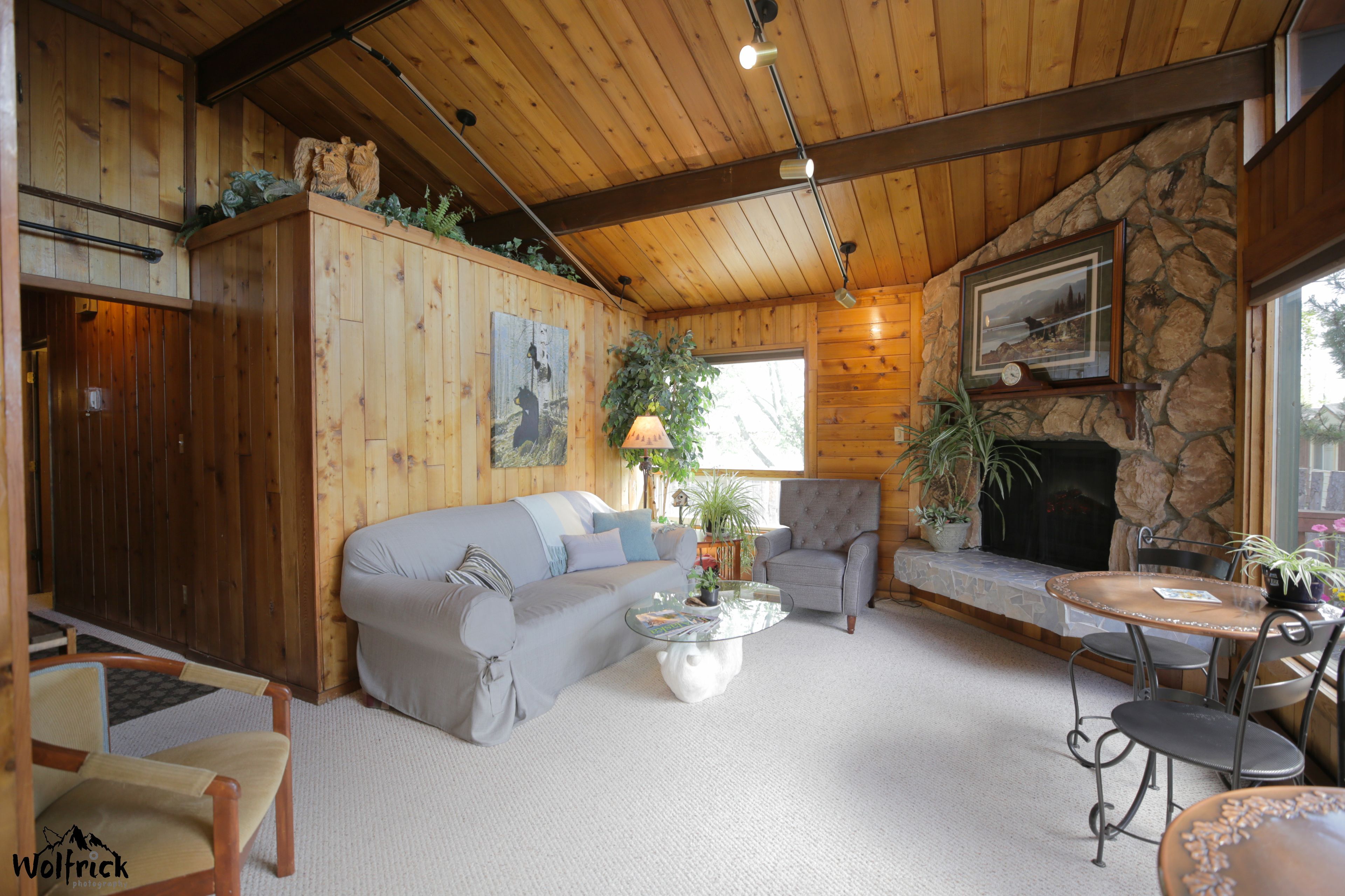 A cozy living room with a stone fireplace, wooden ceiling, and a comfortable sofa.