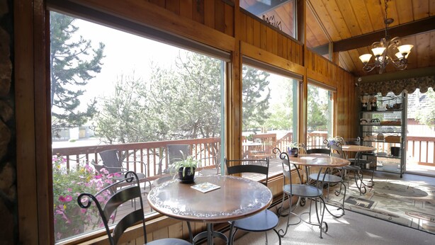 A wooden interior with large windows, a round table, and chairs. - Jewel Lake Bed and Breakfast (Anchorage)