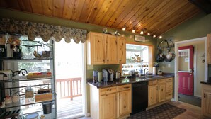 A kitchen with wooden cabinets, a dishwasher, and various kitchen appliances. - Jewel Lake Bed and Breakfast (Anchorage)