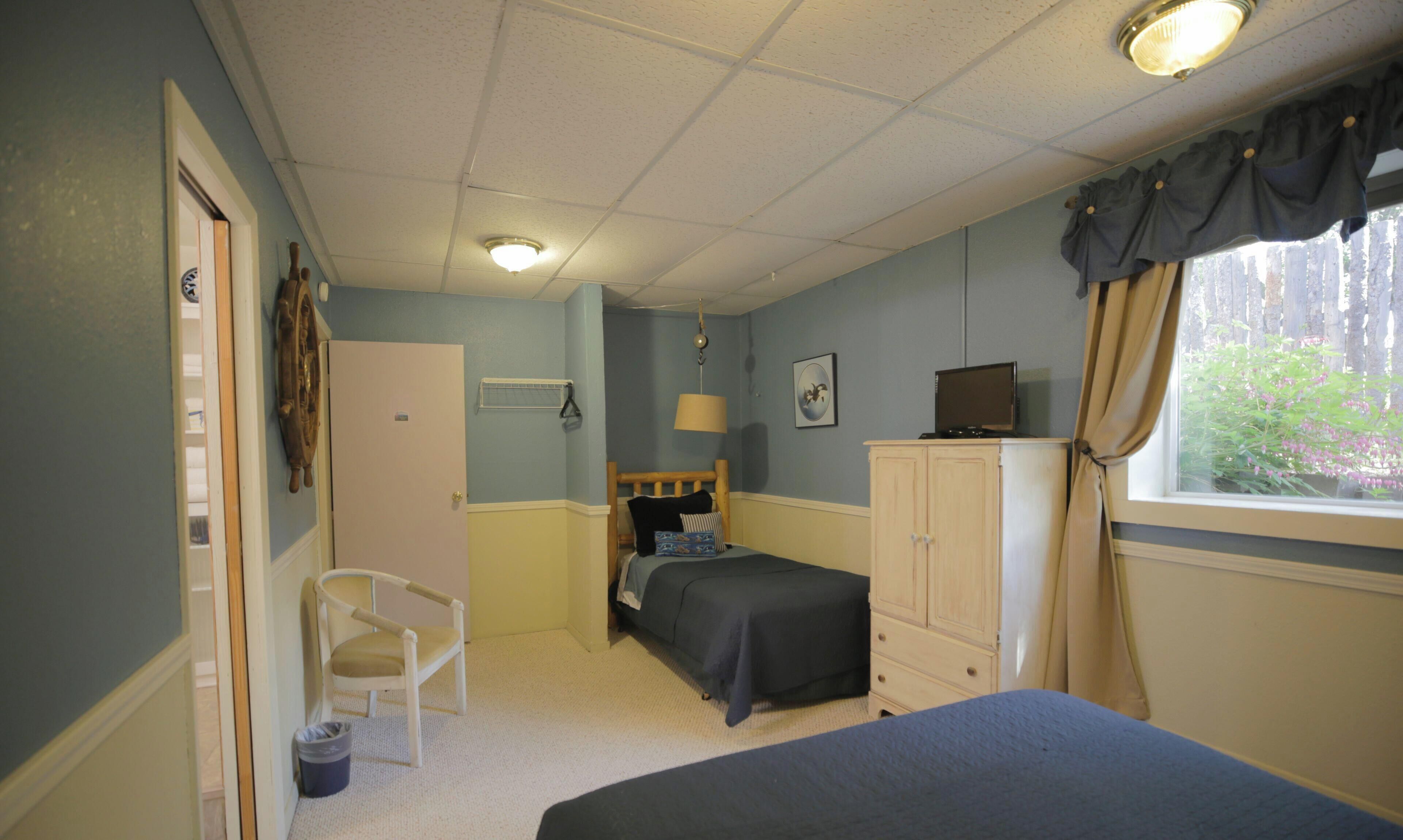 Een slaapkamer met een bed, een stoel, een kledingkast, een raam met gordijnen en een plafondlamp.