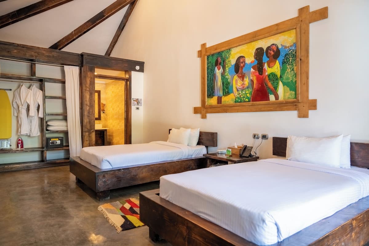 Une chambre d’hôtel avec deux lits, un plafond en bois, un tableau au mur et une salle de bain équipée d’un porte-serviettes.