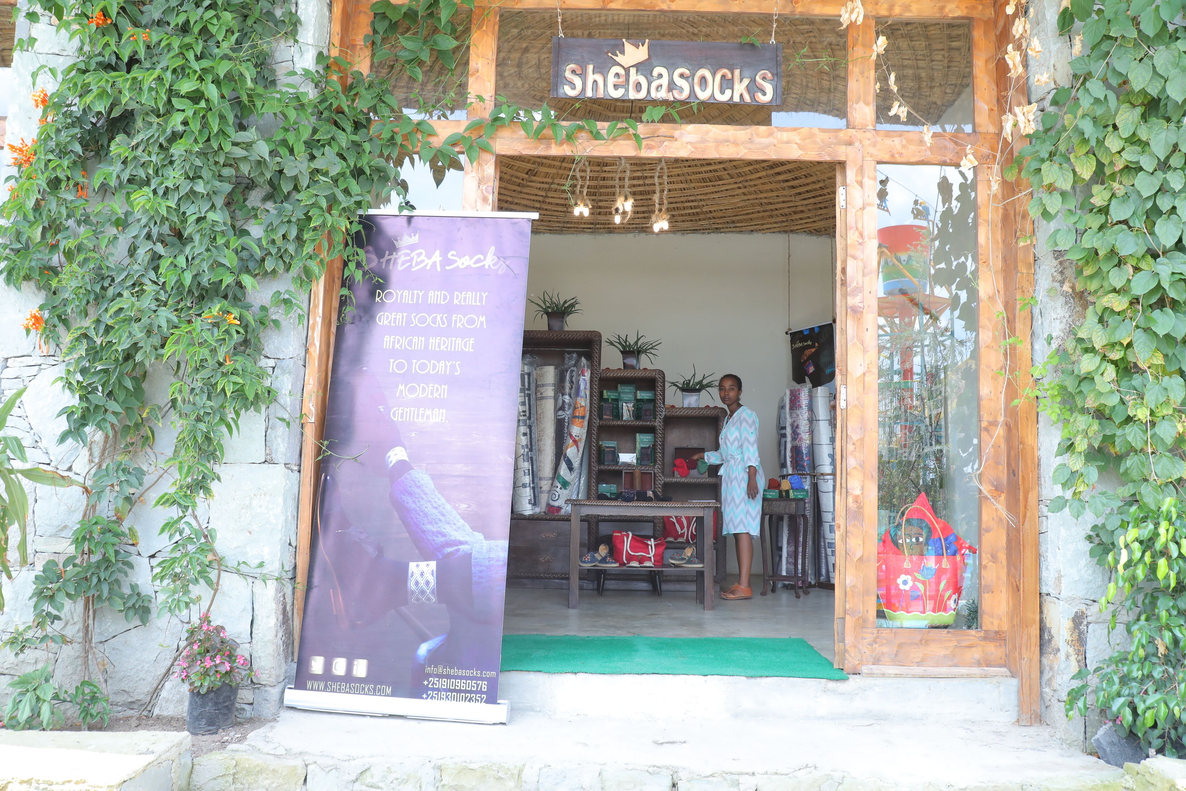 A storefront with a sign reading "Shebasocks" and a large poster advertising "HBA sock" with a website and phone number.