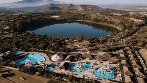 An aerial view of a resort with a large lake, multiple swimming pools, and thatched-roof structures. - Kuriftu Resort & Spa Bishoftu (Bishoftu)