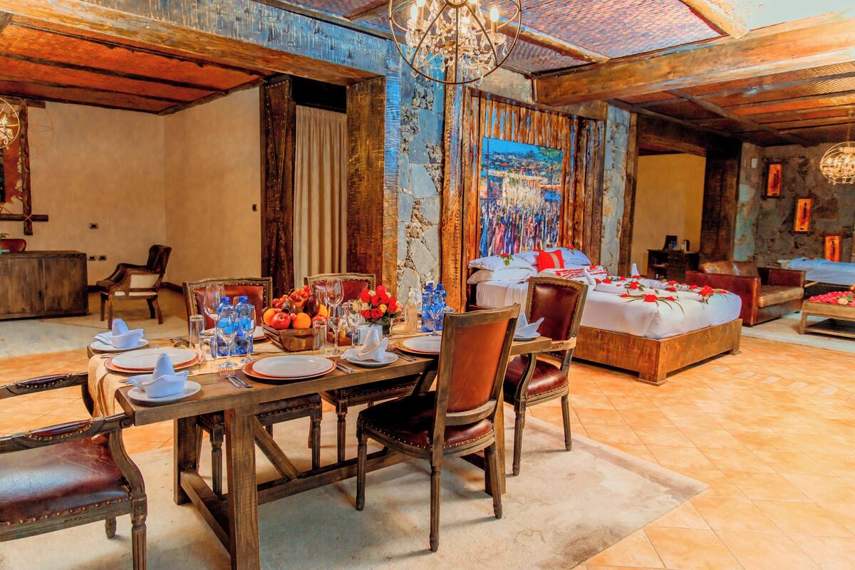 Une salle à manger rustique avec une table en bois dressée pour le repas, entourée de chaises en cuir.