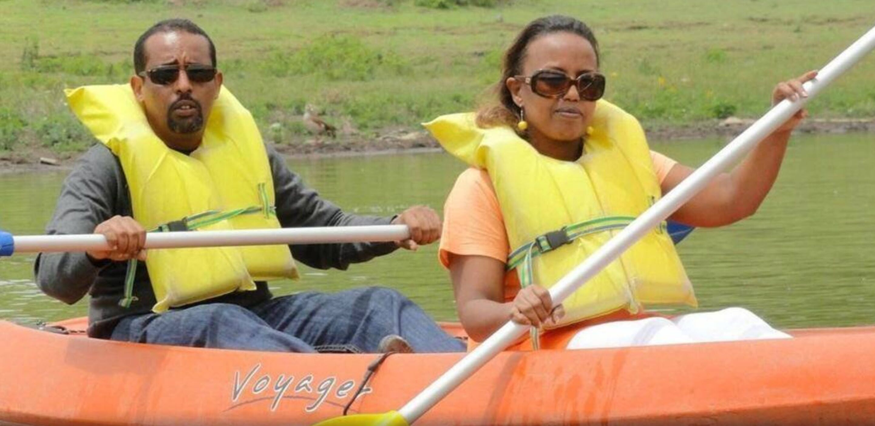 Dues persones en una canoa amb armilles salvavides, remant en un riu tranquil.