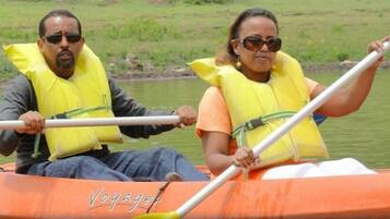 Dues persones en una canoa amb armilles salvavides, remant en un riu tranquil.