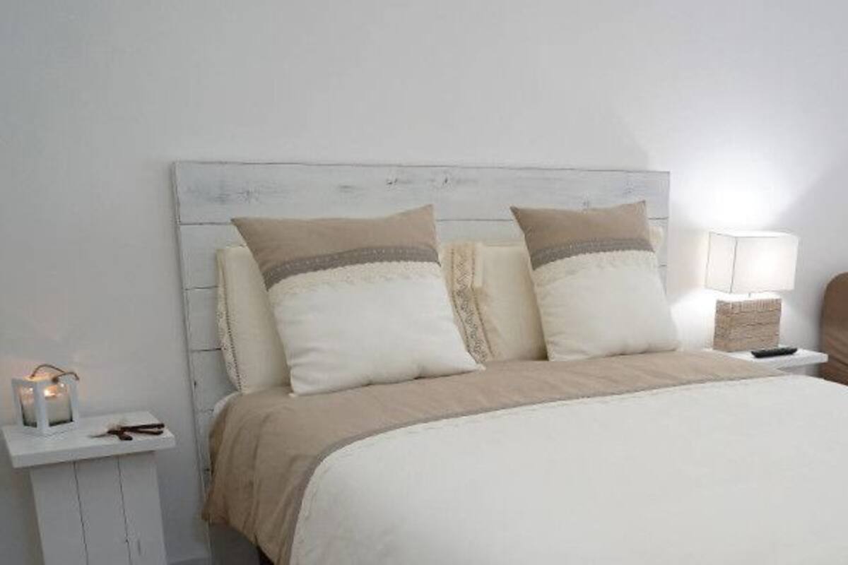 Ein Schlafzimmer mit einem Bett, Nachttischen, einem Sessel und einer Heizung.