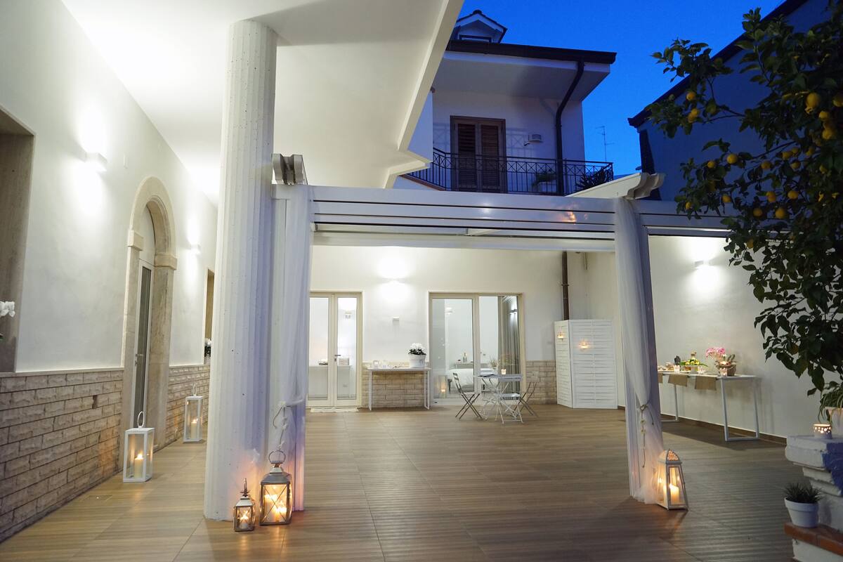 Eine geräumige Außenpatio-Terrasse mit Holzboden, weißen Säulen und Laternen.