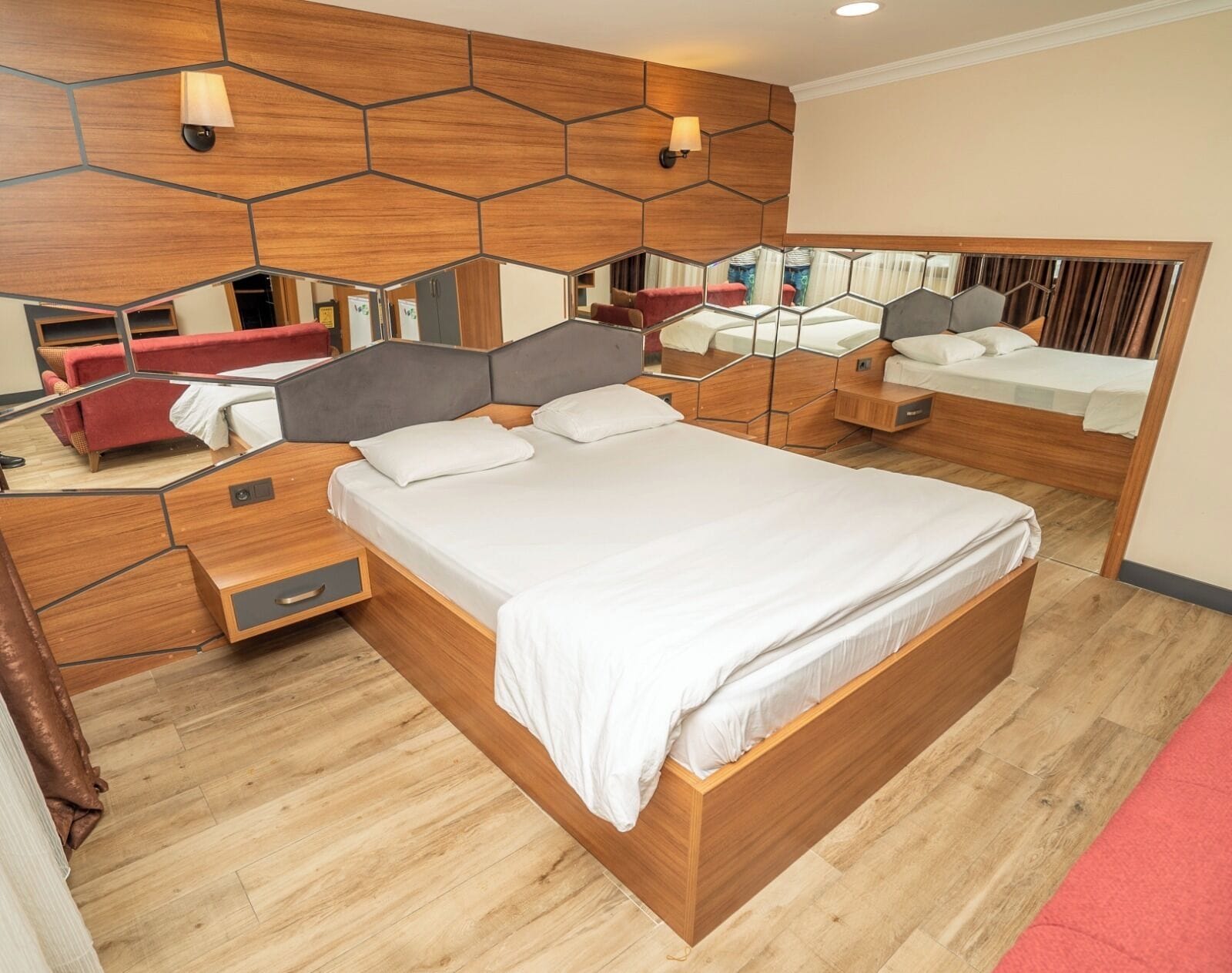 Una camera da letto moderna con un letto grande, un comodino, uno specchio e un divano rosso.