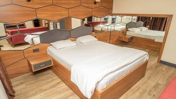 Een moderne slaapkamer met een groot bed, een nachtkastje, een spiegel en een rode bank.