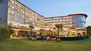 A modern hotel with multiple floors, outdoor seating areas, and a well-lit courtyard. - Swiss-Belresort Pecatu (Pecatu)