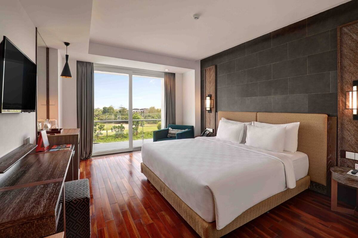 A hotel room with a large bed, a desk, a TV, and a view of the outdoors.