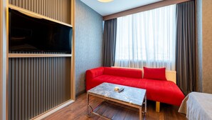 A hotel room with a red sofa, a small table, a television, and a window with curtains. -  216 Eagle Palace Suite (Istanbul)
