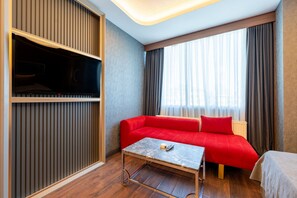 A hotel room with a red sofa, a small table, a television, and a window with curtains. -  216 Eagle Palace Suite (Istanbul)