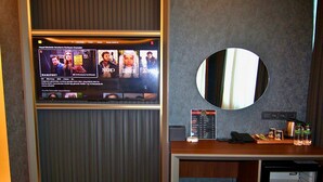 A hotel room with a flat-screen TV displaying a Netflix interface, a mirror, a minibar, and a small refrigerator. -  216 Eagle Palace Suite (Istanbul)