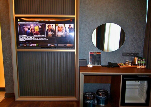 A hotel room with a flat-screen TV displaying a Netflix interface, a mirror, a minibar, and a small refrigerator. -  216 Eagle Palace Suite (Istanbul)