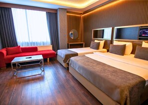 A hotel room with a red sofa, two single beds, a small table, and a TV. -  216 Eagle Palace Suite (Istanbul)