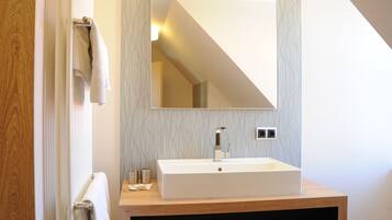 Un baño moderno con tocador de madera, un espejo grande y un perchero para toallas.
