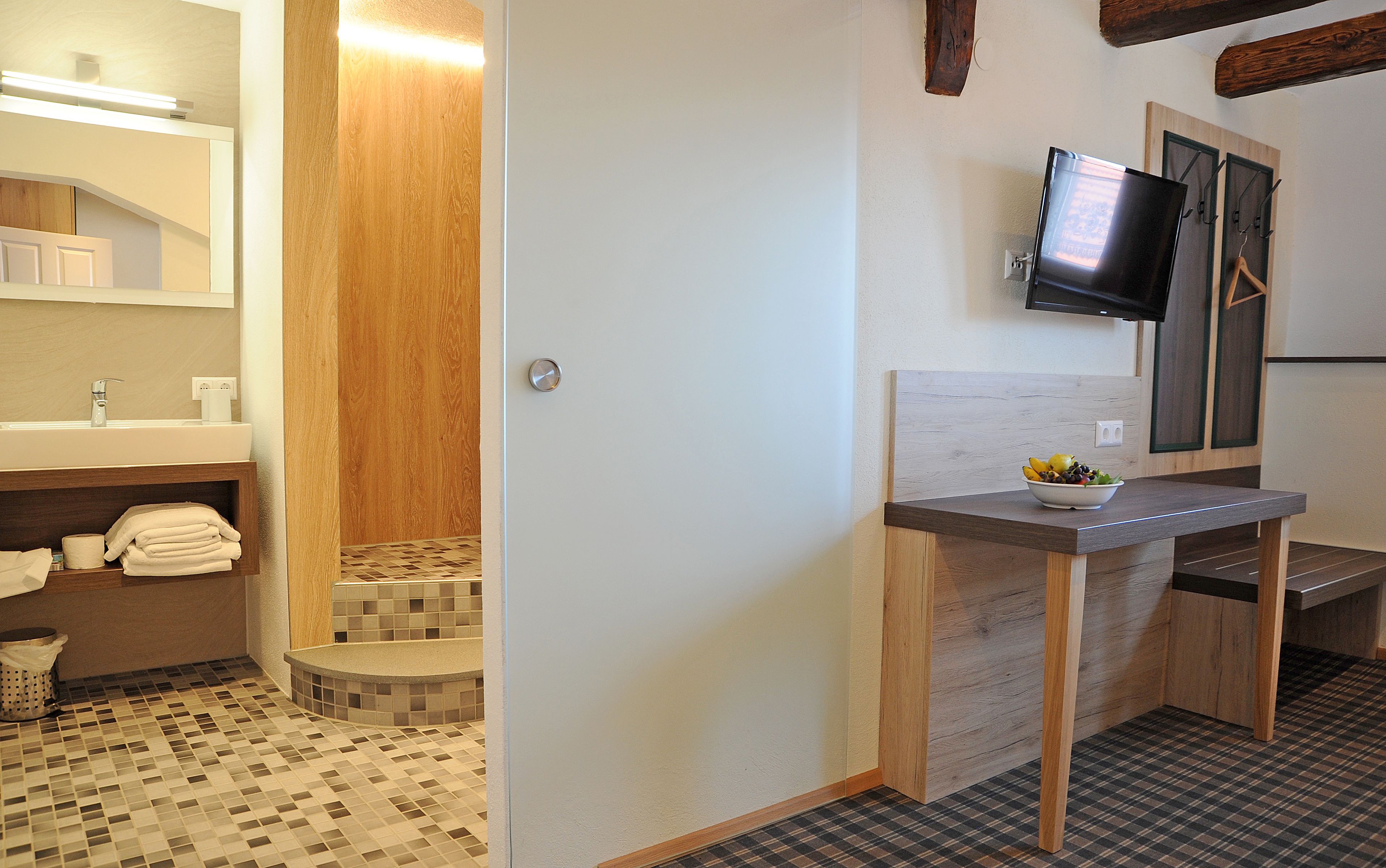 Une salle de bain équipée d’un lavabo, de toilettes et d’une petite marche menant à l’espace douche.