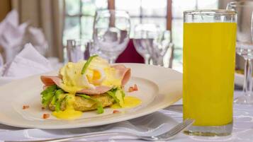 A dining table with a plate of food and a glass of yellow beverage.