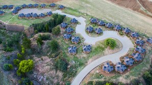 An aerial view of a residential area with a winding road connecting clusters of houses with similar architecture.