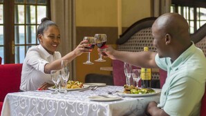 A dining table with plates of food, wine glasses, and a bottle of wine.