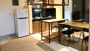 A modern kitchen with a white LG refrigerator, wooden cabinets, a black countertop, and a dining area with a wooden table and black chairs.