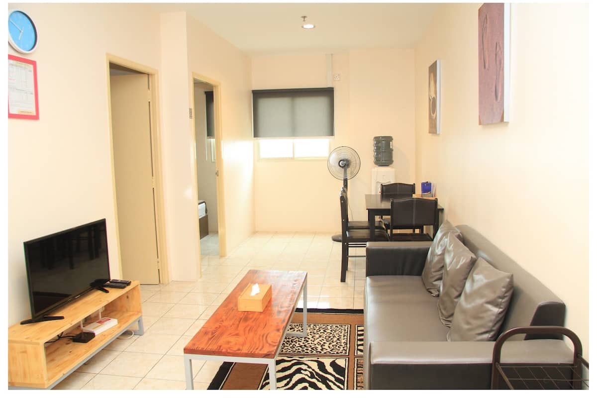 A living room with a TV, sofa, coffee table, and a fan.