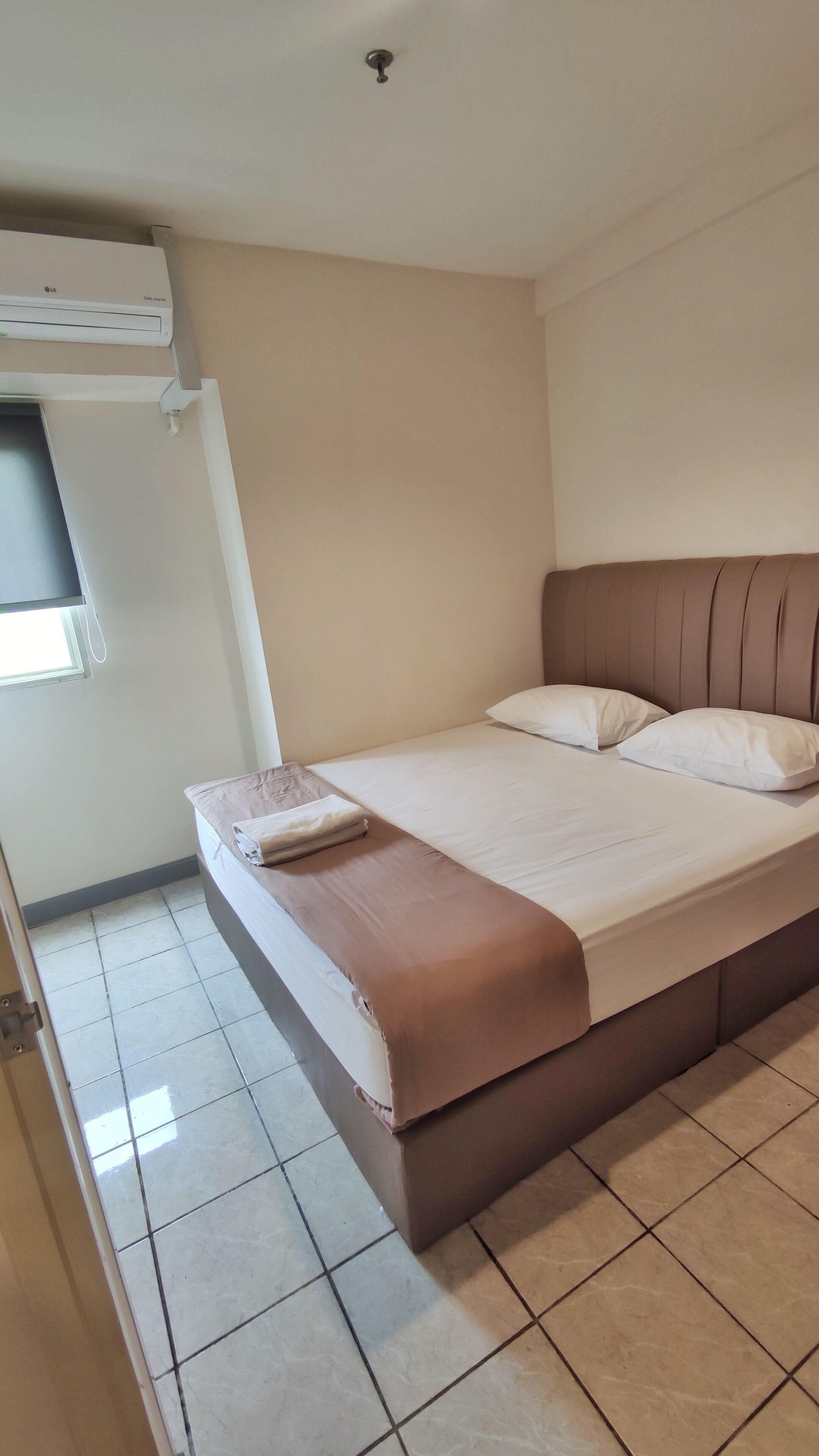 A bedroom with a bed, a window, and an air conditioning unit.