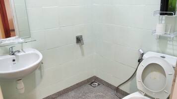 A small bathroom with a sink, toilet, and shower.