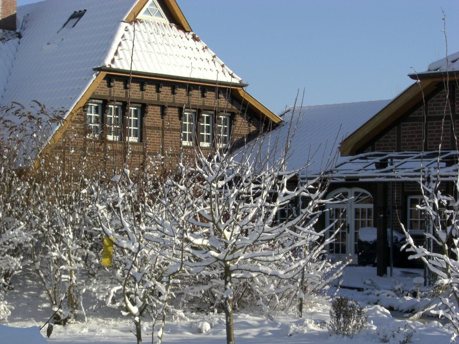 En traditionel bjælkehytte med et stejlt tag, træfacade og mange vinduer.