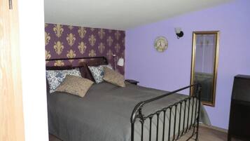Ein Schlafzimmer mit Bett, Spiegel, einer Uhr und einer Lampe.