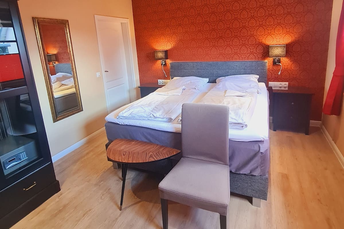 A bedroom with two beds, a chair, a dresser, and a mirror.