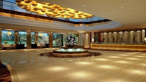 Un hall d’entrée spacieux agrémenté d’une fontaine centrale, de colonnes décoratives et d’un espace détente avec des canapés.
