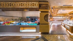 Un hall d’hôtel spacieux, doté d’un sol en marbre, d’un comptoir de réception central et d’un espace buffet proposant une variété de plats.