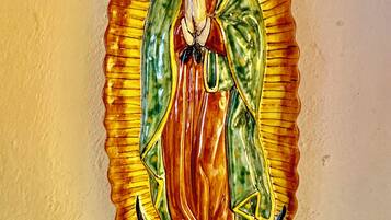 A religious icon with a scalloped frame, depicting a figure in a red robe and green cloak, set against a plain wall.