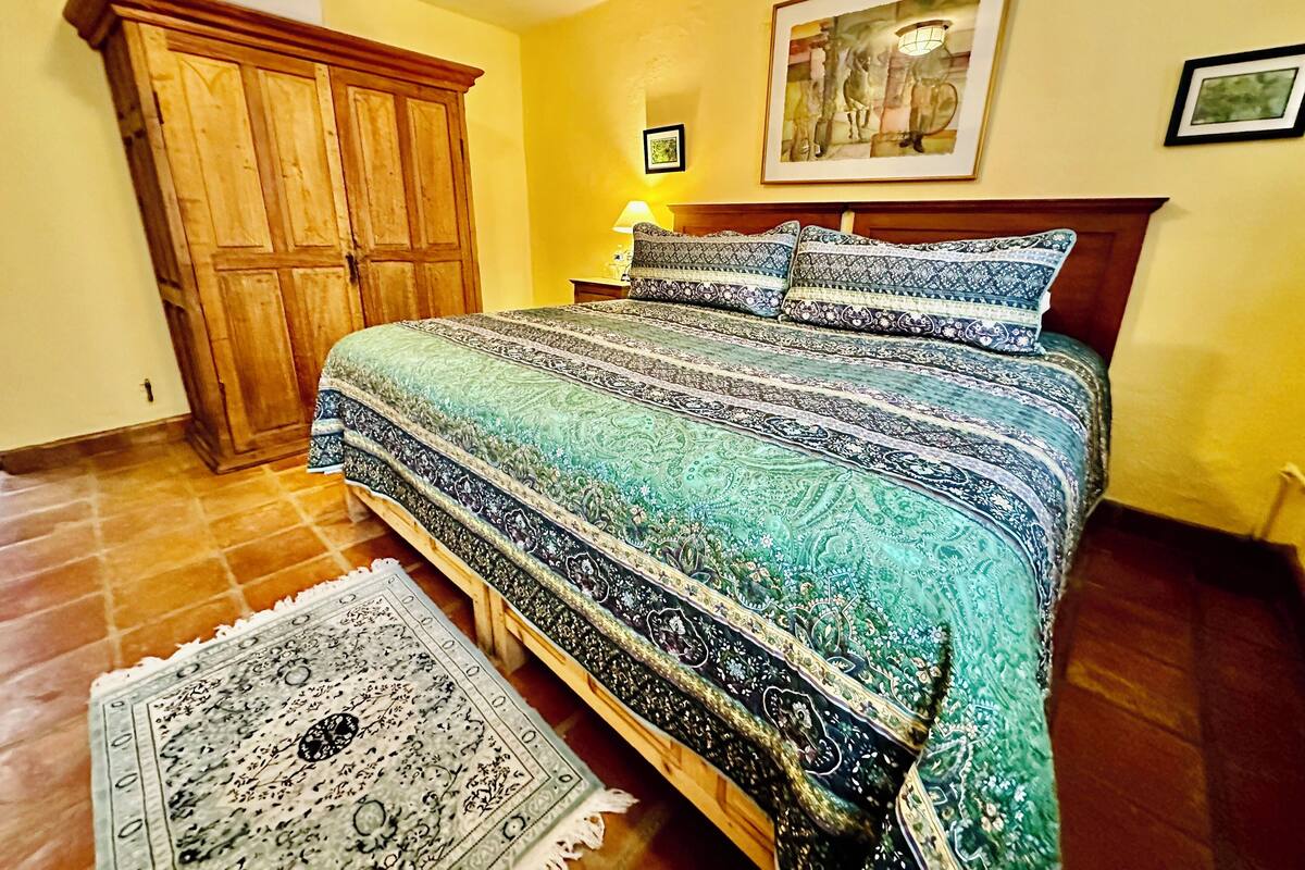 Un dormitorio con una cama grande, armario de madera y una alfombra.