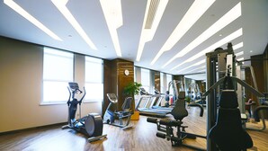 Un gimnasio con equipo de ejercicio, ventanas amplias y suelo de madera.