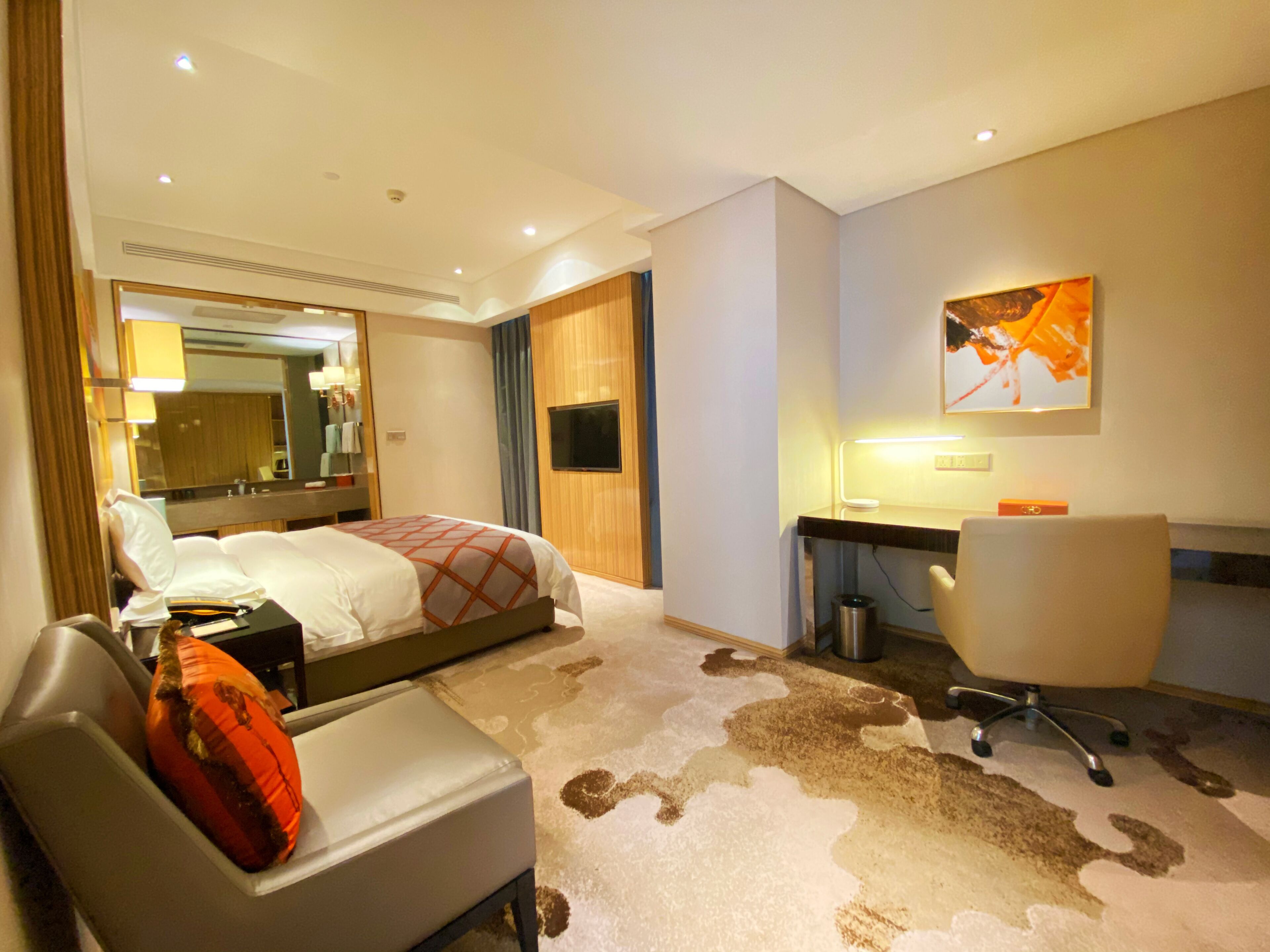 Une chambre d’hôtel équipée d’un lit, d’un bureau, d’une chaise, d’une télévision et d’un miroir.