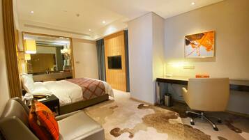 Une chambre d’hôtel équipée d’un lit, d’un bureau, d’une chaise, d’une télévision et d’un miroir.