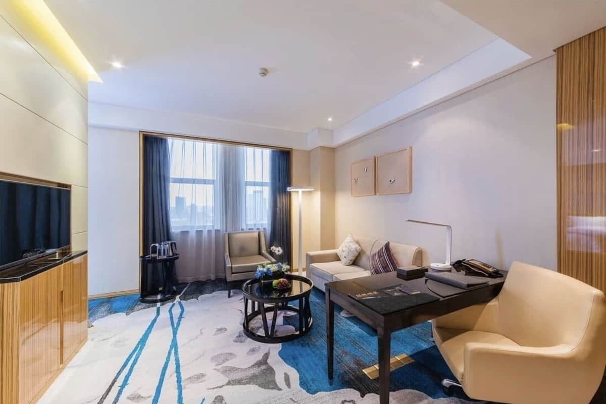 Una habitación de hotel moderna con sofá, mesa de comedor, mesita de centro y televisión.