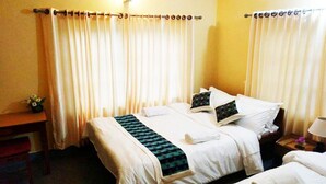 A hotel room with two beds, a desk, and a nightstand with a lamp. - Hotel Nana Pokhara (Pokhara)
